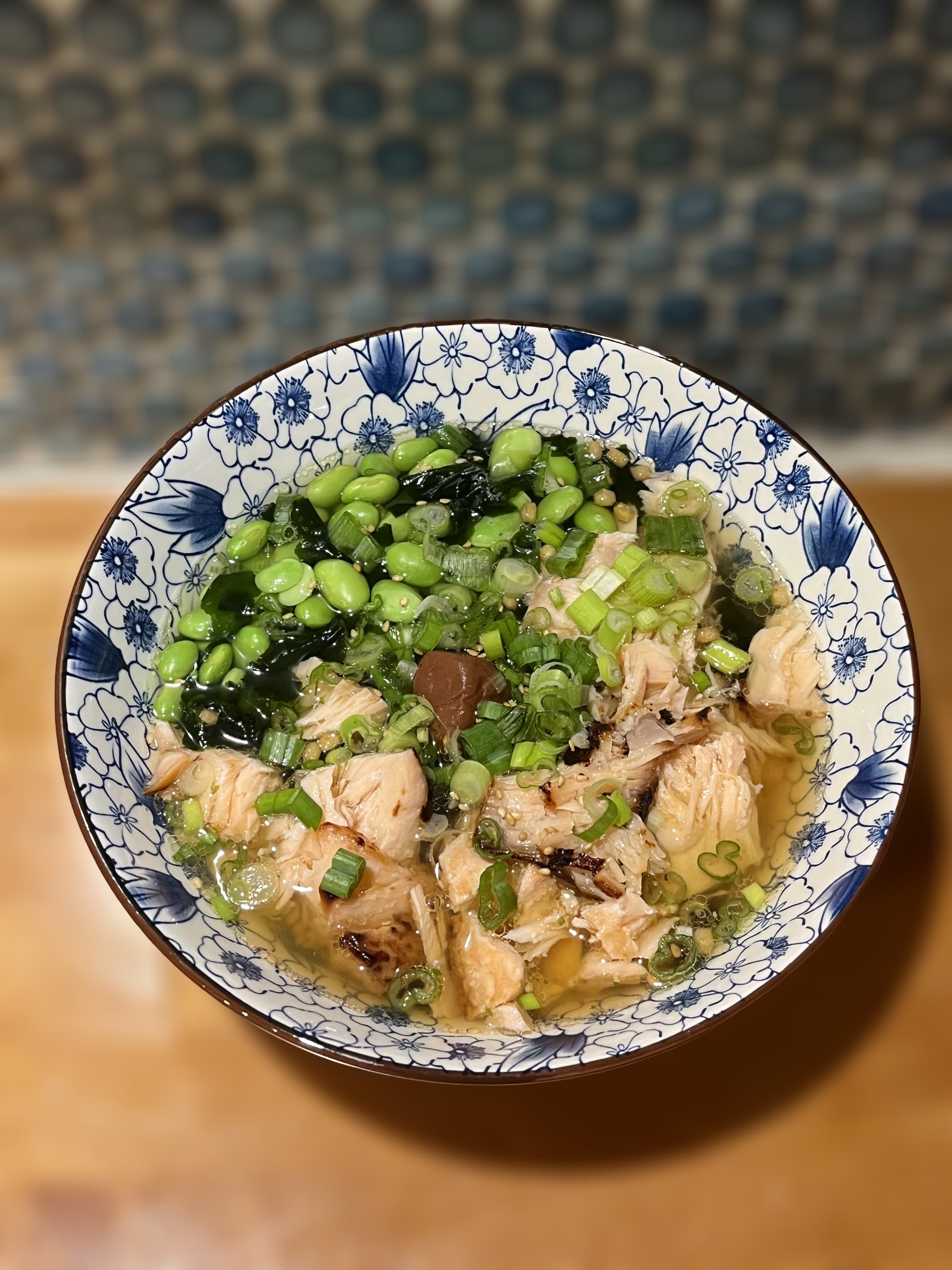 Miso salmon ochazuke in a blue-and-white bowl, topped with edamame, green onions, wakame, and flaky salmon.